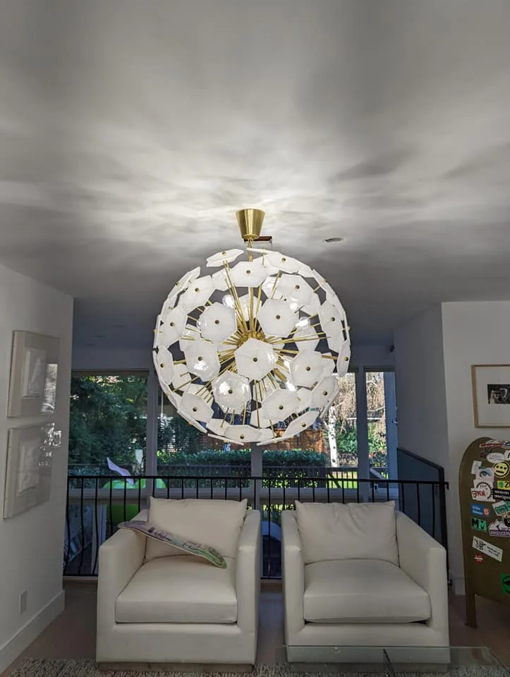 Decorative white and brass pendant light above a living room seating area