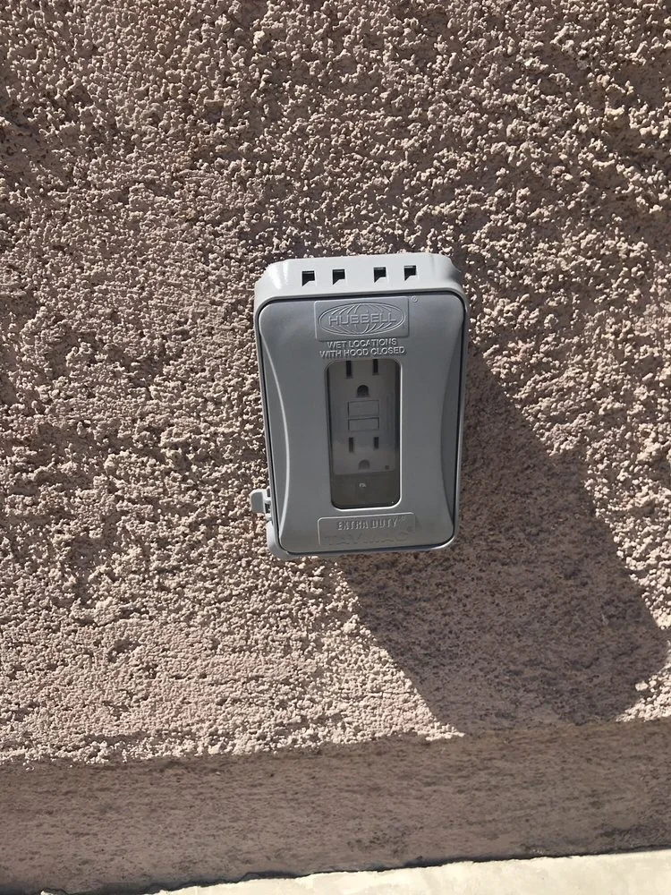 Exterior electrical outlet protected by a gray weatherproof cover